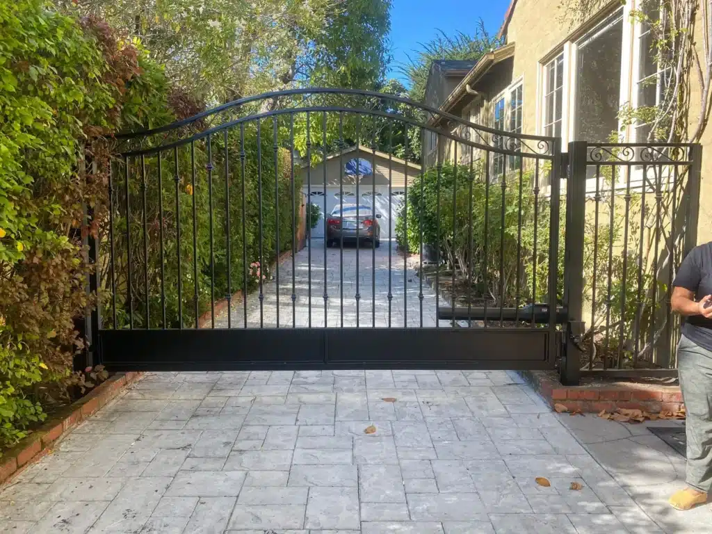 Photo Of An Ornamental Black Iron Single Swing Driveway Entry Gate Open To A Garage