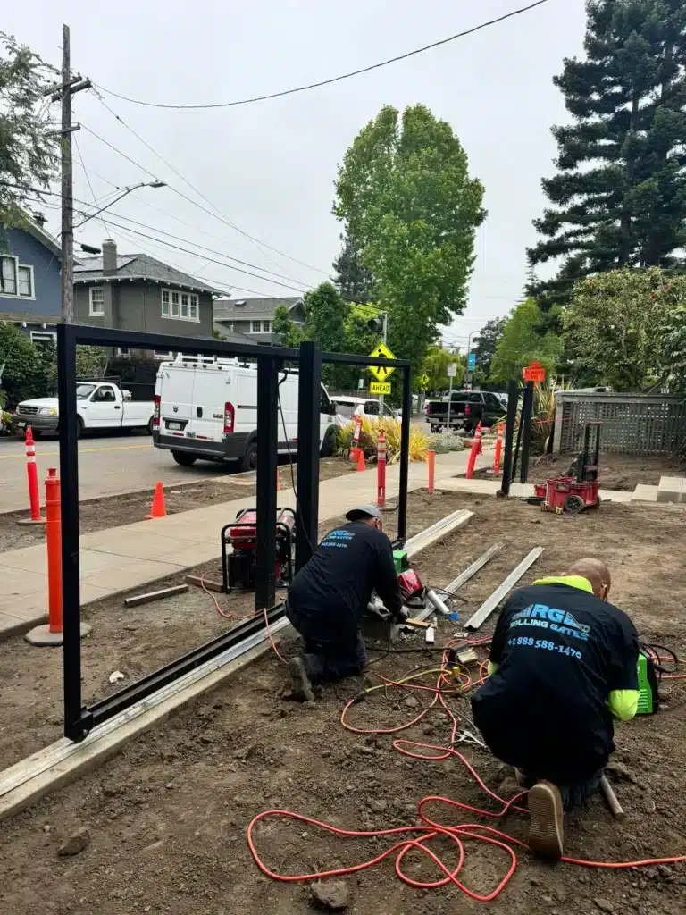 Photo Of Technicians Assembling A Heavy Steel Sliding Gate Frame Track On Dirt Ground
