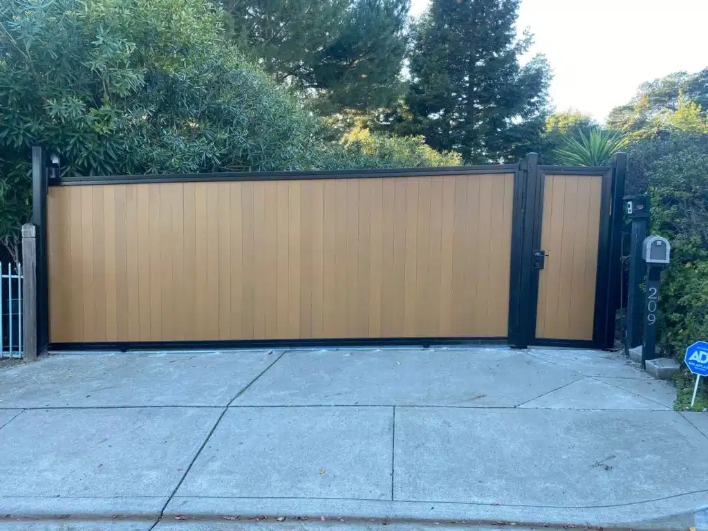Photo Of A Modern Light Brown Wood Sliding Driveway Privacy Gate With Black Metal Trim