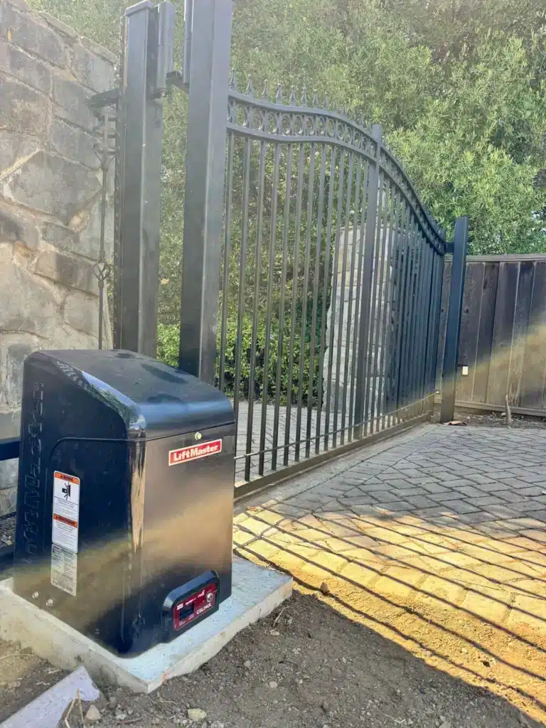Photo Of Liftmaster Gate Opener Motor Set On Concrete Beside Arched Metal Gate